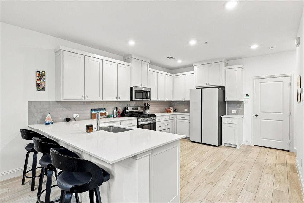 4833 Lunker Street, McKinney, TX 75071 Bright, sleek, and made for gathering. The kitchen features crisp white cabinetry, stainless appliances, and an expansive island that anchors the heart of the home.