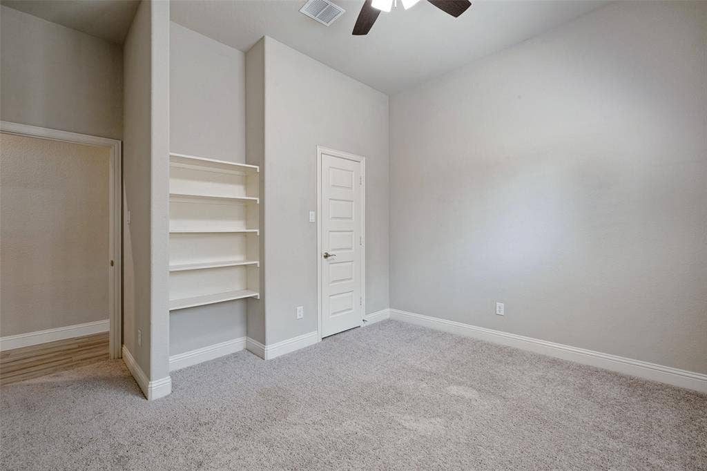 6001 Allison Drive, Midlothian, TX 76065 This secondary bedroom features built-in shelving and a walk in closet as well as a ceiling fan.