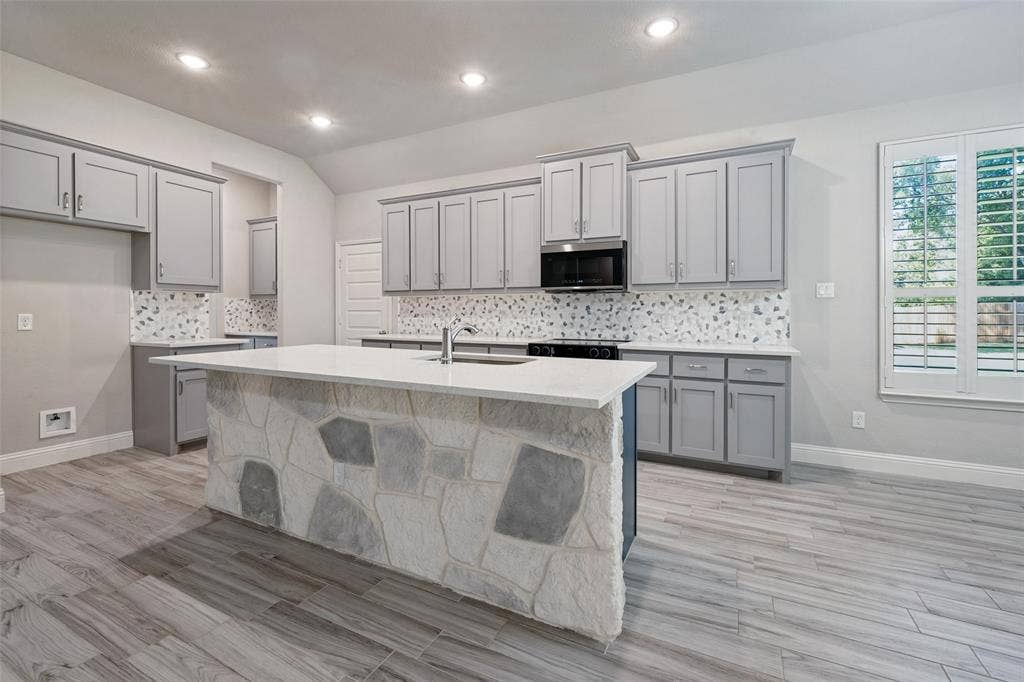 6001 Allison Drive, Midlothian, TX 76065 Kitchen featuring a blown in stone facade on the island with a quartz countertop, integrated appliances, and wood-look tile flooring. Of special intrest is the flex oven which converts to a double oven.