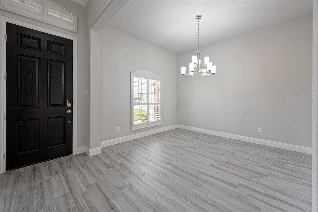 6001 Allison Drive, Midlothian, TX 76065 Wood-look tile flooring, arched window with plantation shutters, contemporary chandelier, and a paneled entry door with transom window