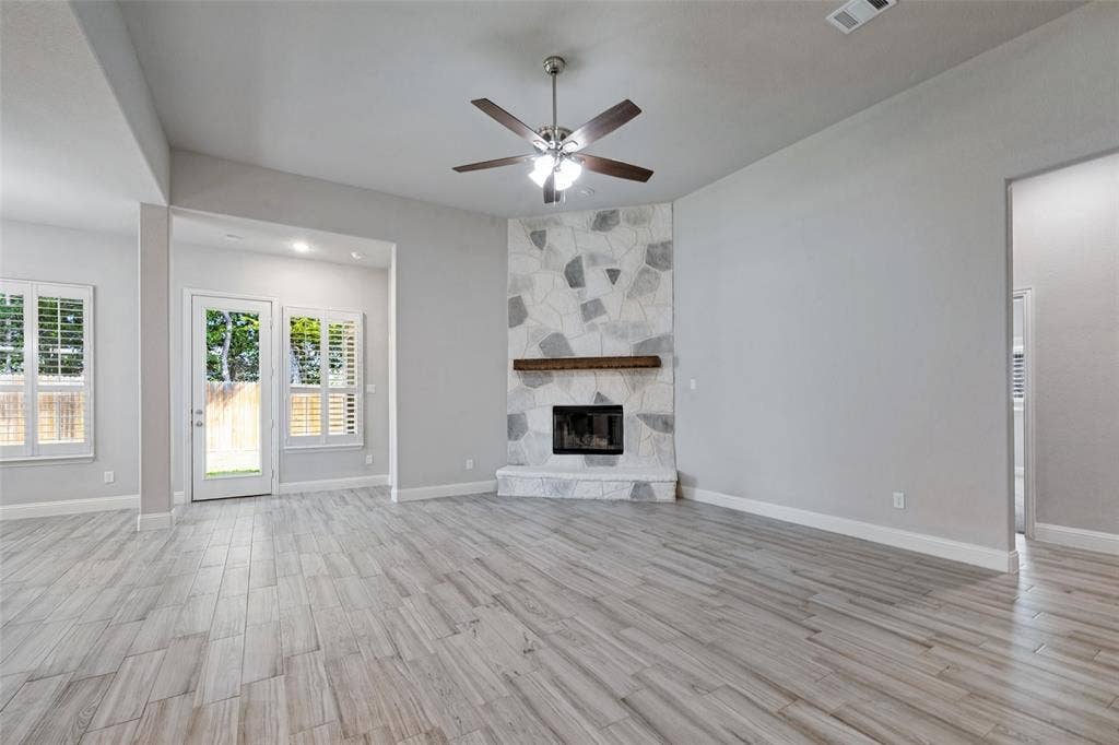 6001 Allison Drive, Midlothian, TX 76065 Vaulted ceiling with a ceiling fan, fireplace with hearth, and white plantation shutters on windows. This door leads you out to the spacious covered porch.