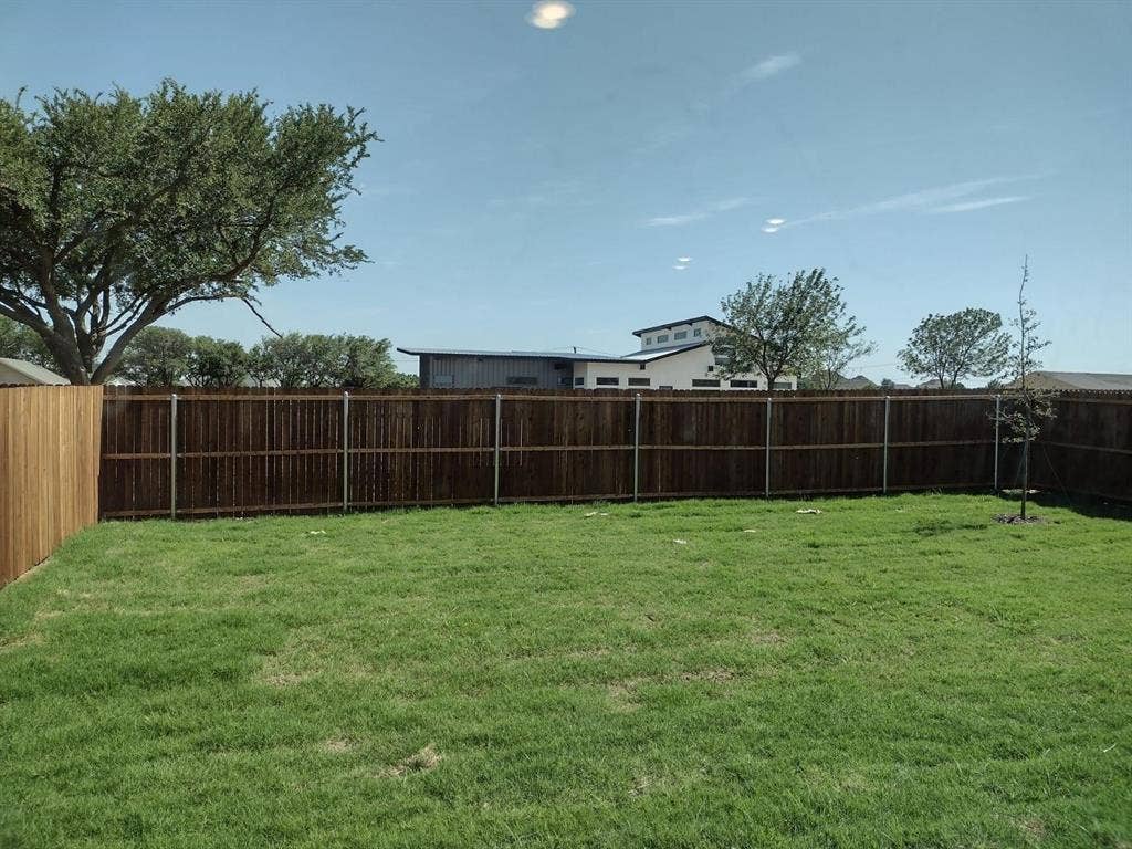 Expansive grassy yard area with a wood privacy fence