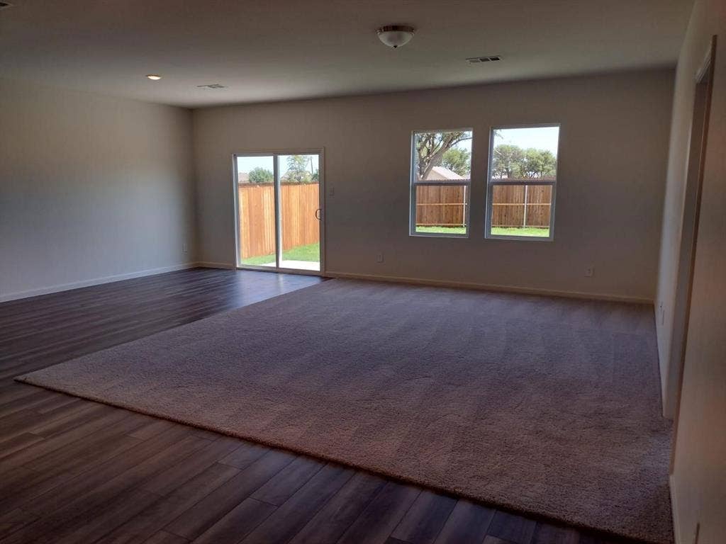 Spacious living area featuring wood-finish flooring, recessed lighting, and a sliding glass door
