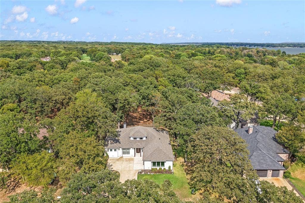 128 Saint Andrews Drive E, Mabank, TX 75156 Aerial perspective showcasing a sprawling residential property enveloped by dense, mature tree canopy