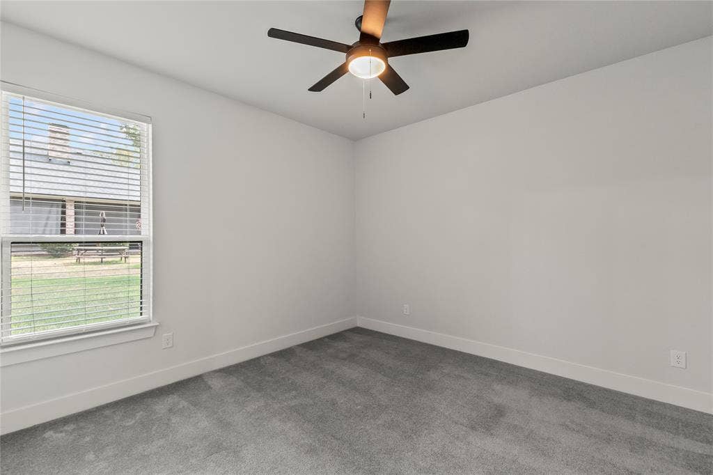 128 Saint Andrews Drive E, Mabank, TX 75156 Bright bedroom featuring neutral wall finishes, plush carpeting, a ceiling fan with integrated lighting, and large double-hung window allowing natural light