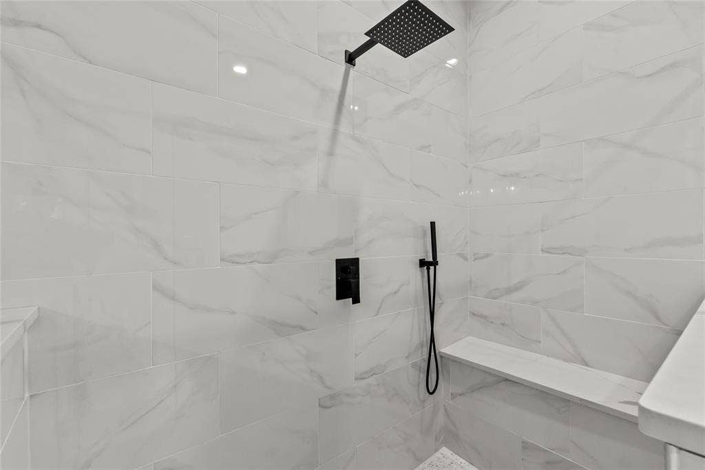 128 Saint Andrews Drive E, Mabank, TX 75156 Tiled shower with a rainfall showerhead, handheld sprayer, and built-in bench