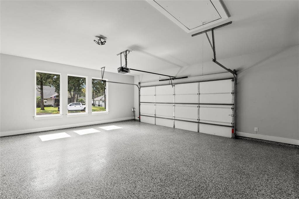 128 Saint Andrews Drive E, Mabank, TX 75156 Garage with speckled epoxy flooring, three windows, an automatic garage door opener, and an attic access panel