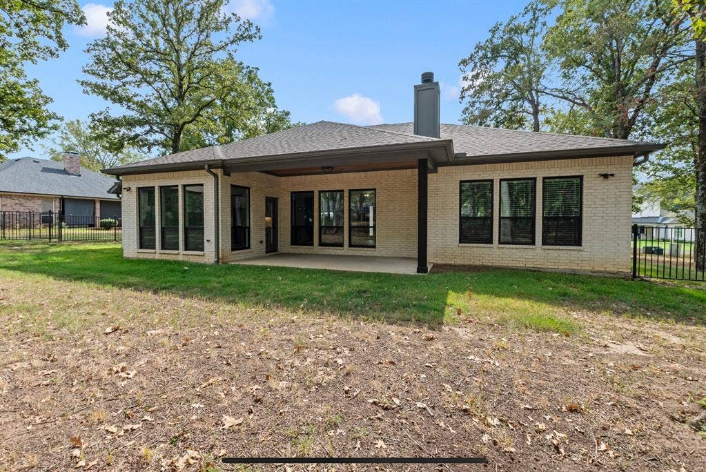 128 Saint Andrews Drive E, Mabank, TX 75156 White brick exterior with a covered patio, multiple large windows, and a dark shingle roof