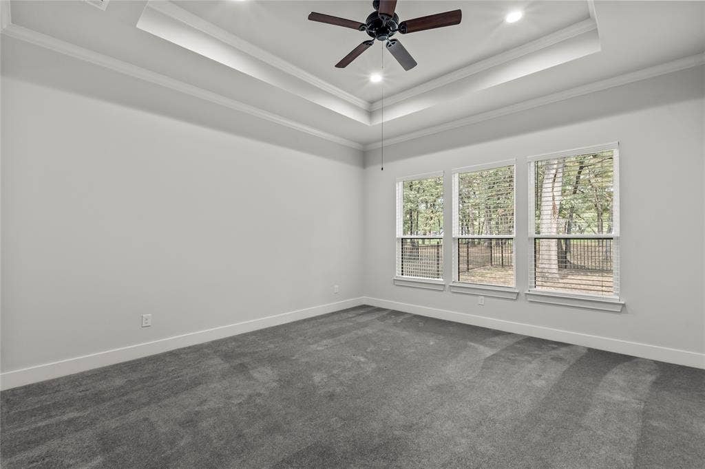 128 Saint Andrews Drive E, Mabank, TX 75156 Tray ceiling with recessed lighting and a ceiling fan, three large windows, and neutral carpeting