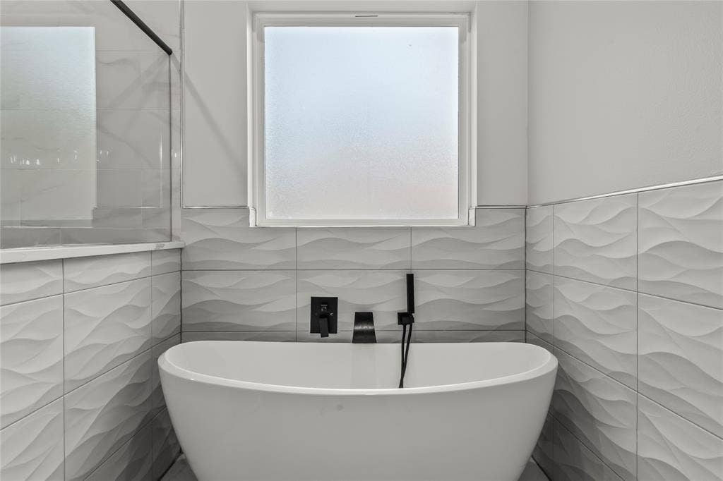 128 Saint Andrews Drive E, Mabank, TX 75156 Modern spa-inspired soaking tub with matte black wall-mounted faucet and hand-shower fixture