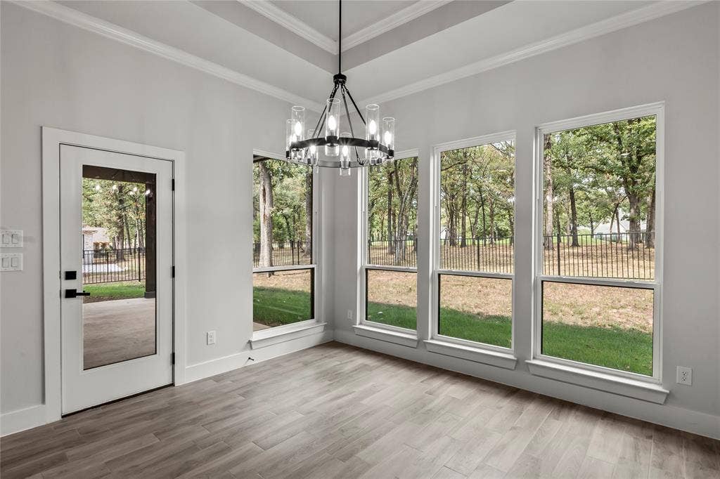 128 Saint Andrews Drive E, Mabank, TX 75156 Tray ceiling with crown molding, wood-finish flooring, glass-paned exterior door, and multiple windows