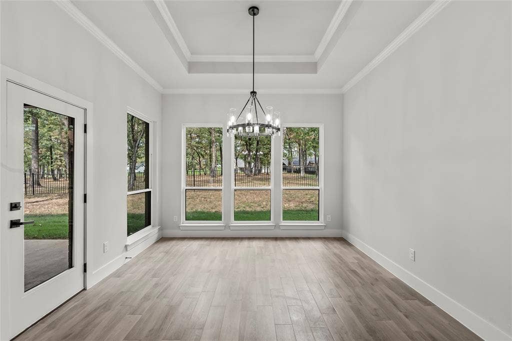 128 Saint Andrews Drive E, Mabank, TX 75156 Tray ceiling with crown molding, wood-finish flooring, full-light exterior door, triple pane windows, and a contemporary chandelier