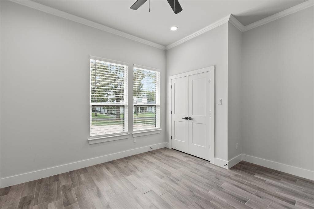 128 Saint Andrews Drive E, Mabank, TX 75156 Neutral wall tones, wood-finish flooring, two large windows, white paneled doors, and a ceiling fan with integrated lighting