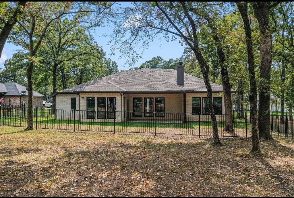 128 Saint Andrews Drive E, Mabank, TX 75156 Brick exterior with a covered patio, multiple large windows, and a fenced yard
