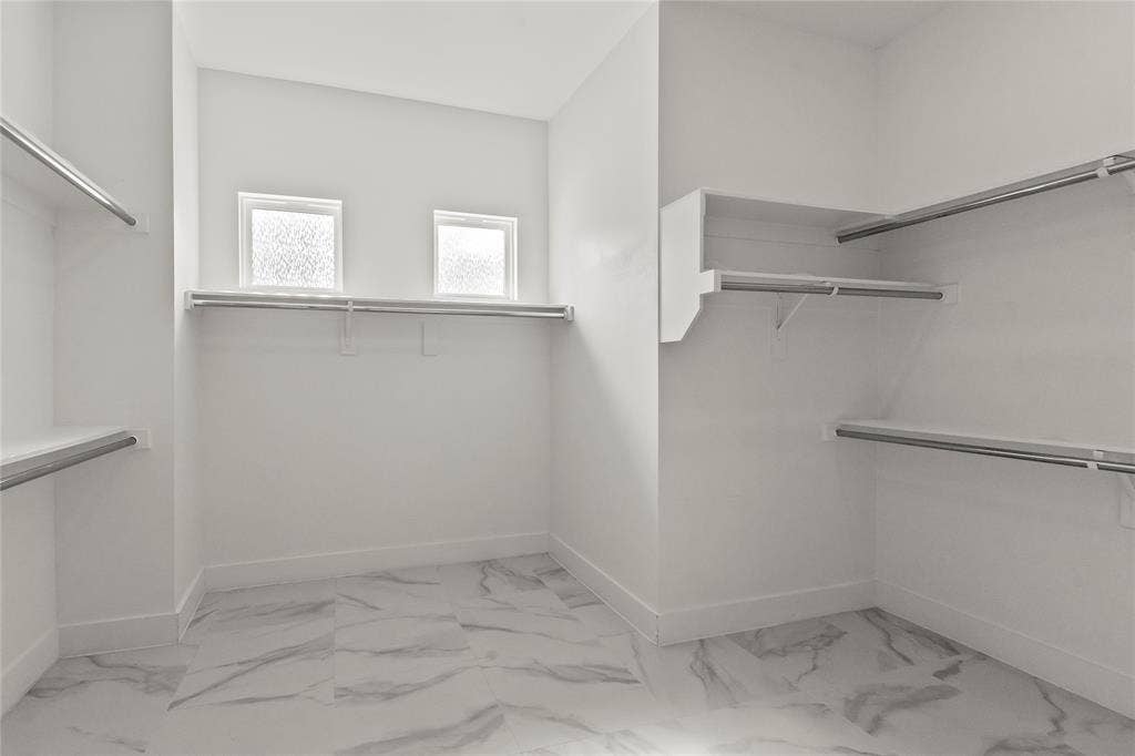 128 Saint Andrews Drive E, Mabank, TX 75156 Walk-in closet featuring white walls, white-finish built-in shelving, two windows, and patterned tile flooring