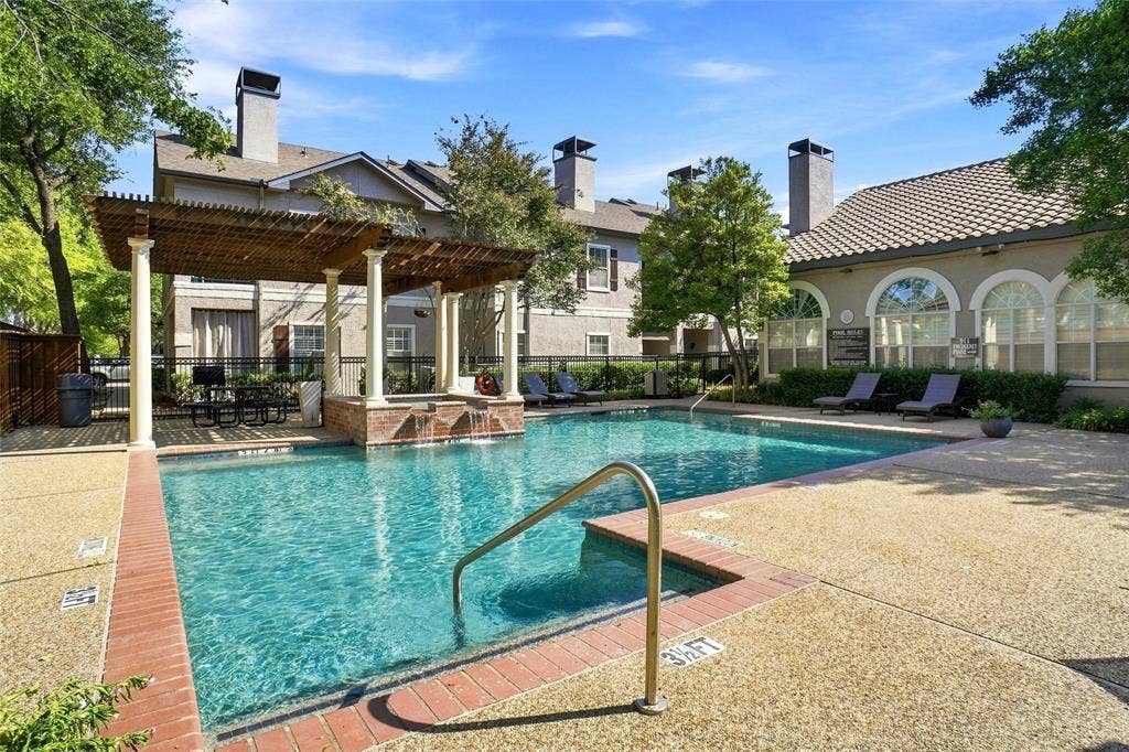 2601 Preston Road, #4103, Plano, TX 75093 Outdoor swimming pool with integrated spa and water feature, surrounded by exposed aggregate concrete decking and brick coping