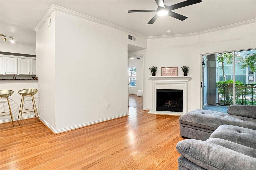 2601 Preston Road, #4103, Plano, TX 75093 Wood-finish flooring throughout, a built-in fireplace with mantel, crown molding, and a ceiling fan with integrated lighting