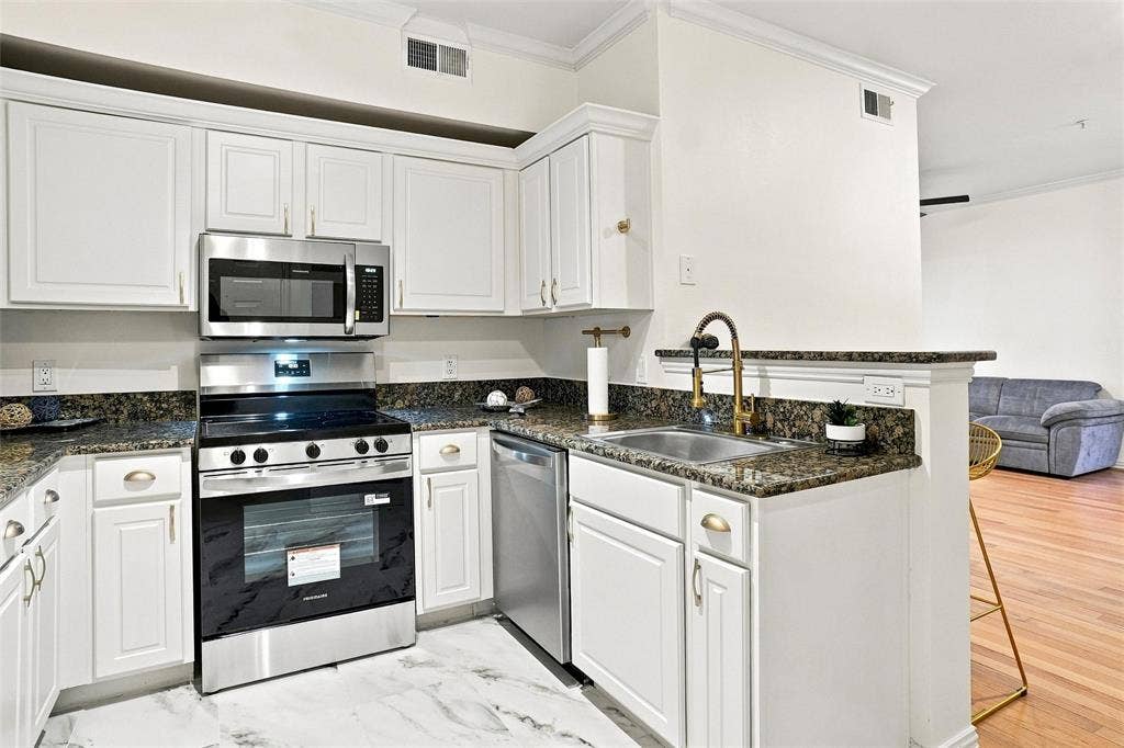 2601 Preston Road, #4103, Plano, TX 75093 Kitchen featuring white cabinetry, stainless steel appliances, granite countertops, an undermount sink with a brass-finish faucet, and marble-look flooring
