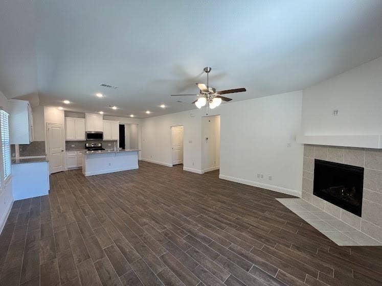 1408 Rendyn Street, Anna, TX 75409 Open-concept living area with wood-finish flooring, a tiled fireplace, and recessed lighting