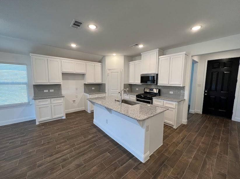 1408 Rendyn Street, Anna, TX 75409 Spacious kitchen featuring white cabinetry, granite countertops, tile backsplash, stainless steel appliances, and a central island with an undermount sink