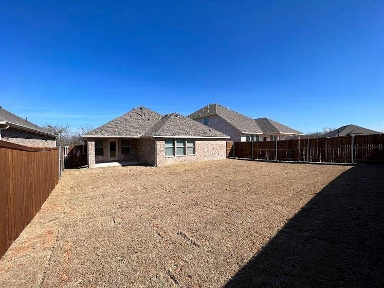 1408 Rendyn Street, Anna, TX 75409 Expansive backyard with a full privacy fence, brick exterior, and covered patio