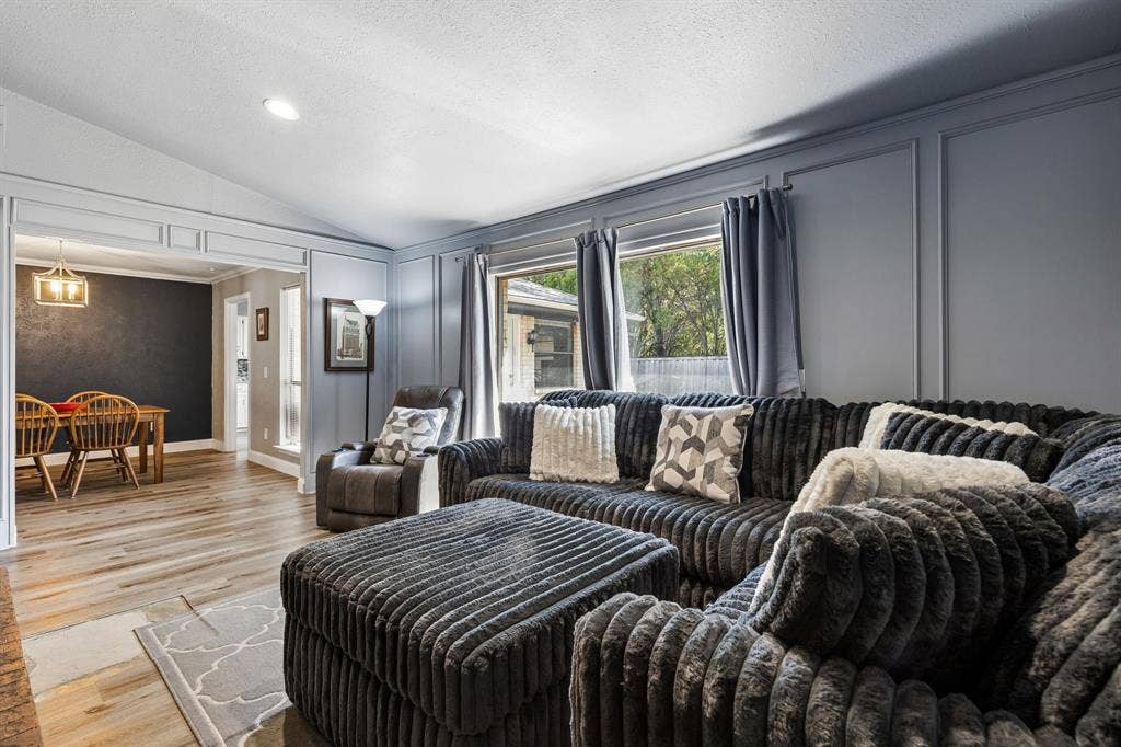 Wood-finish flooring throughout, vaulted ceiling, recessed lighting, and decorative wall paneling