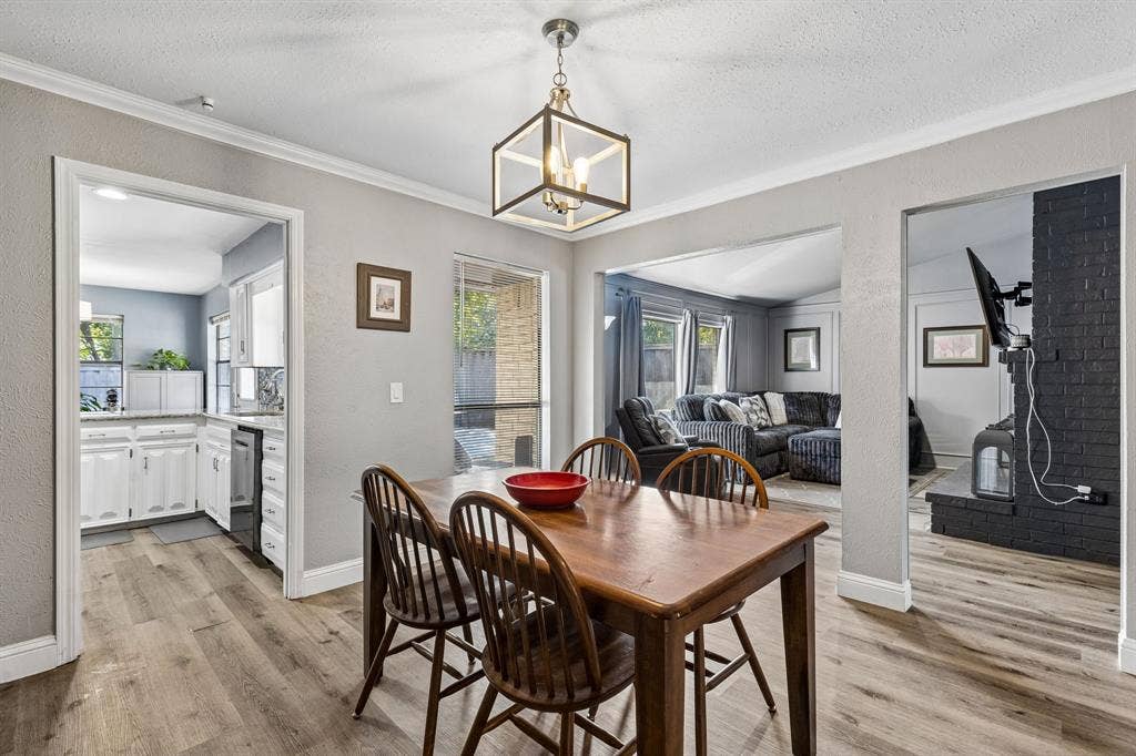 Spacious dining area featuring wood-finish flooring, a modern geometric chandelier, and direct access to the kitchen