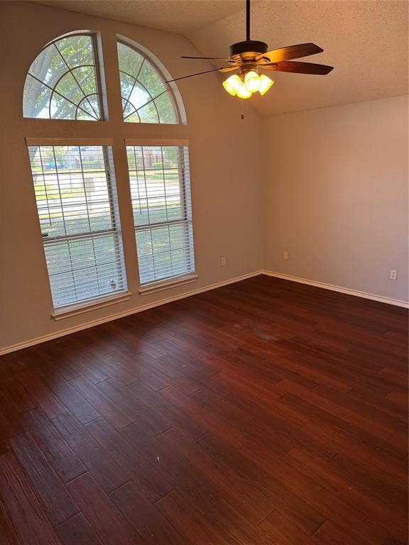 1025 Boardwalk Street, Midlothian, TX 76065 Empty room with a textured ceiling, lofted ceiling, ceiling fan, and dark wood-type flooring
