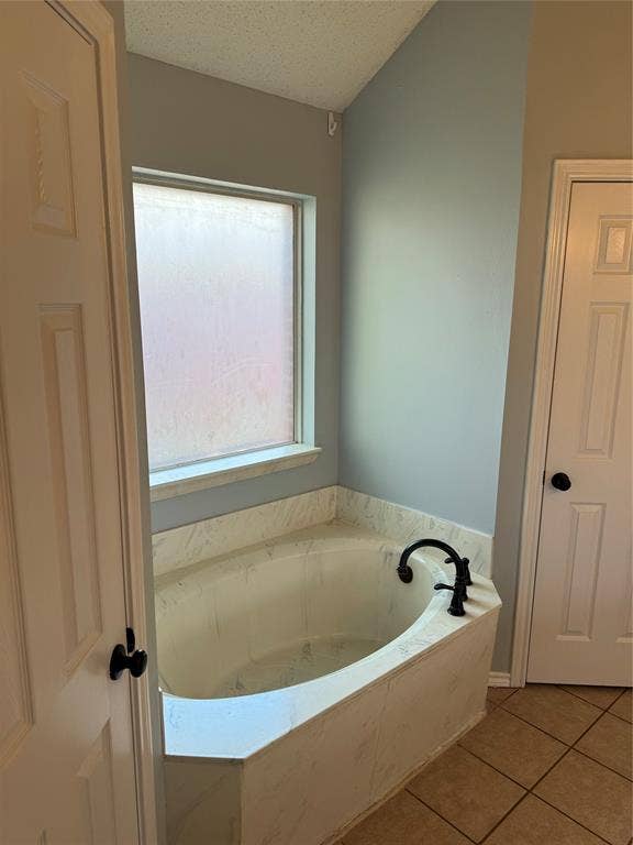 1025 Boardwalk Street, Midlothian, TX 76065 Bathroom with a bath to relax in, a textured ceiling, and tile flooring