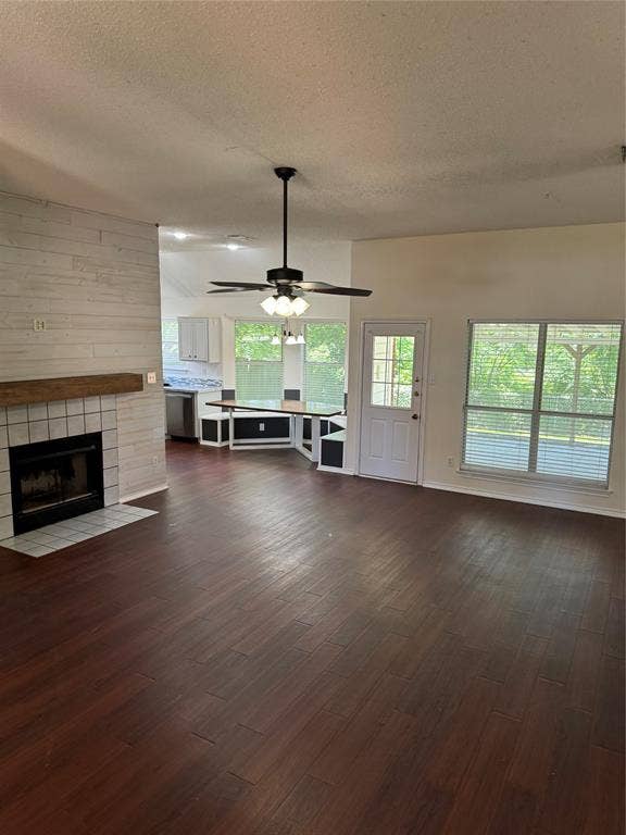 1025 Boardwalk Street, Midlothian, TX 76065 Unfurnished living room with a textured ceiling, dark hardwood / wood-style flooring, ceiling fan, and a tiled fireplace