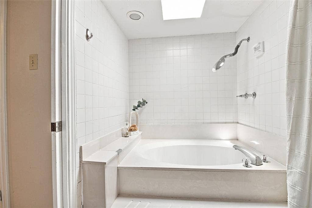 1417 Sun Valley Drive, Garland, TX 75043 Corner soaking tub with polished chrome fixtures and a built-in shelf