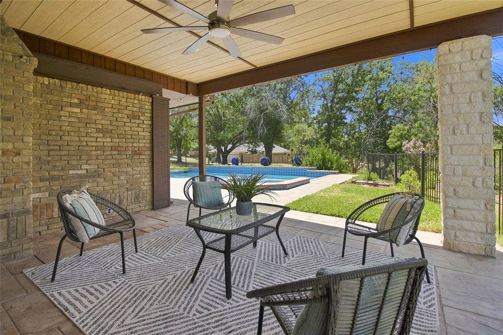 1417 Sun Valley Drive, Garland, TX 75043 Covered patio with a ceiling fan, brick wall, stone column, and a swimming pool