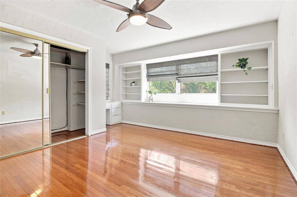 1417 Sun Valley Drive, Garland, TX 75043 Hardwood flooring bedroom, mirrored closet doors, built-in shelving, built-in desk, and a ceiling fan with integrated lighting