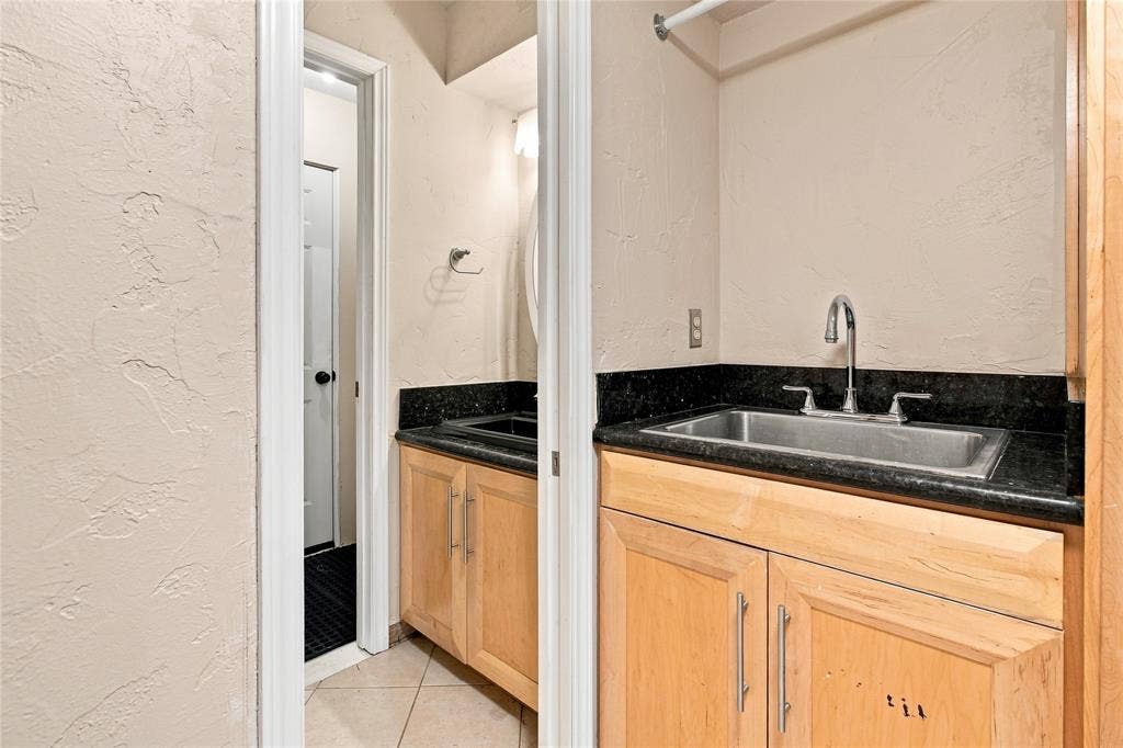 1417 Sun Valley Drive, Garland, TX 75043 Half bath with light-toned wood cabinetry with brushed nickel hardware, dark stone countertop, and stainless steel undermount sink with chrome faucet
