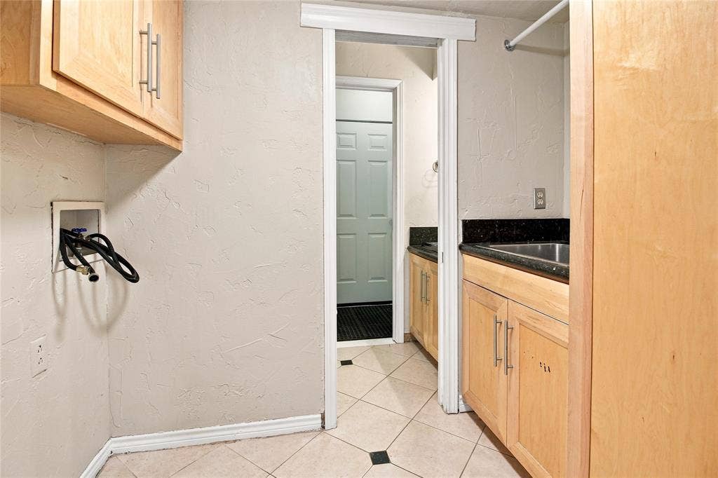1417 Sun Valley Drive, Garland, TX 75043 Light wood-finish cabinetry, stainless steel sink, dark stone-finish countertop, and tiled flooring