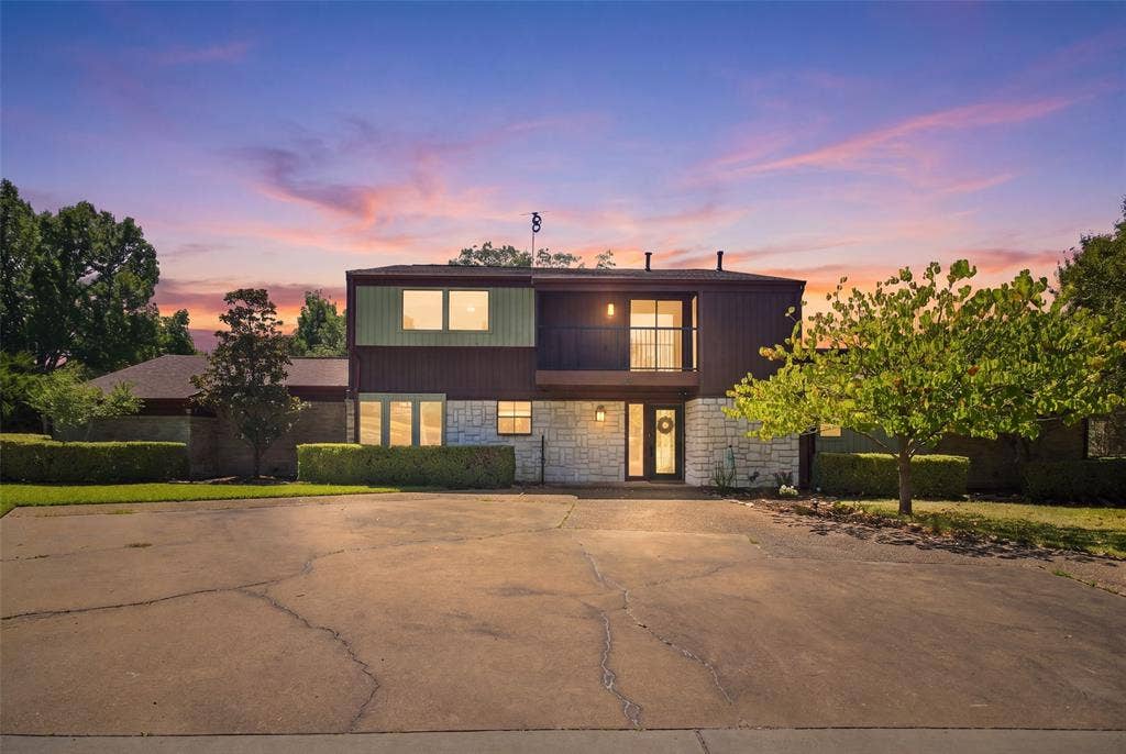 1417 Sun Valley Drive, Garland, TX 75043 Multi-level exterior with stone and siding accents, featuring a second-story balcony with metal railing, a prominent front entry, and a paved driveway
