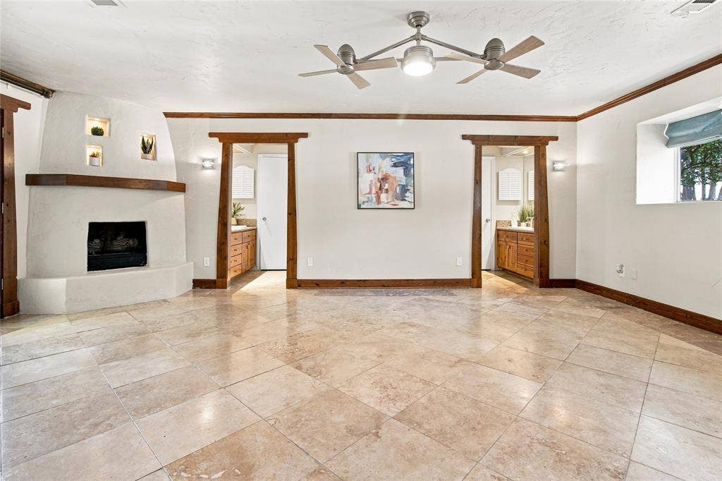 1417 Sun Valley Drive, Garland, TX 75043 Primary bedroom with tile flooring, built-in fireplace, exposed wood trim, recessed wall niches, and dual ceiling fans with integrated lighting