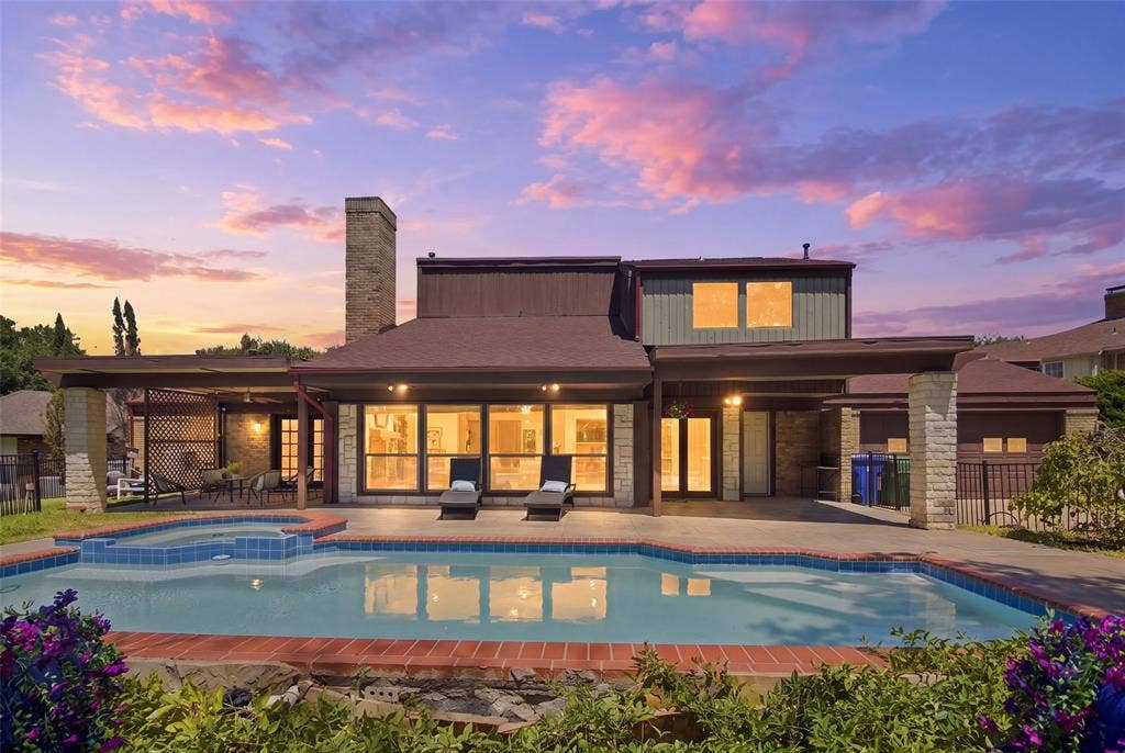 1417 Sun Valley Drive, Garland, TX 75043 Rear exterior featuring a swimming pool, integrated spa, covered patio, full-height windows, and a brick chimney