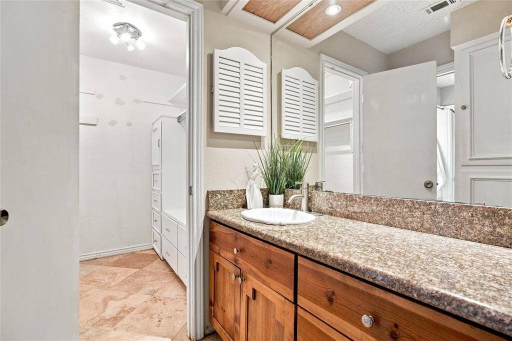 1417 Sun Valley Drive, Garland, TX 75043 Vanity with a single basin, wood cabinetry, and a stone-finish countertop