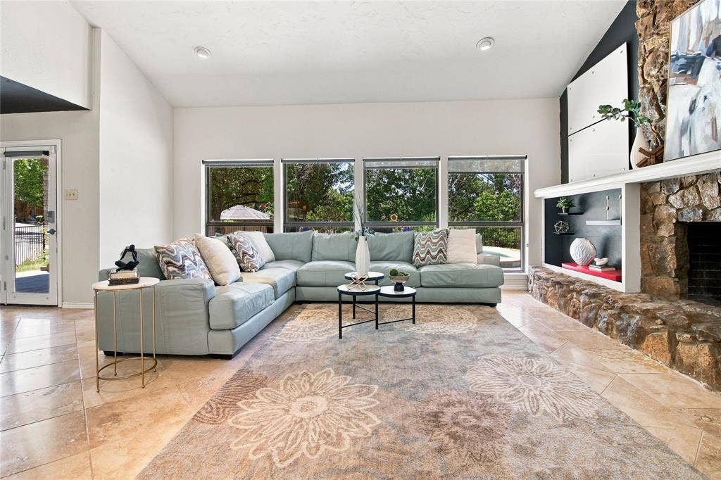 1417 Sun Valley Drive, Garland, TX 75043 Vaulted ceiling, stone-clad fireplace with mantel, built-in shelving, tile flooring, and multiple windows
