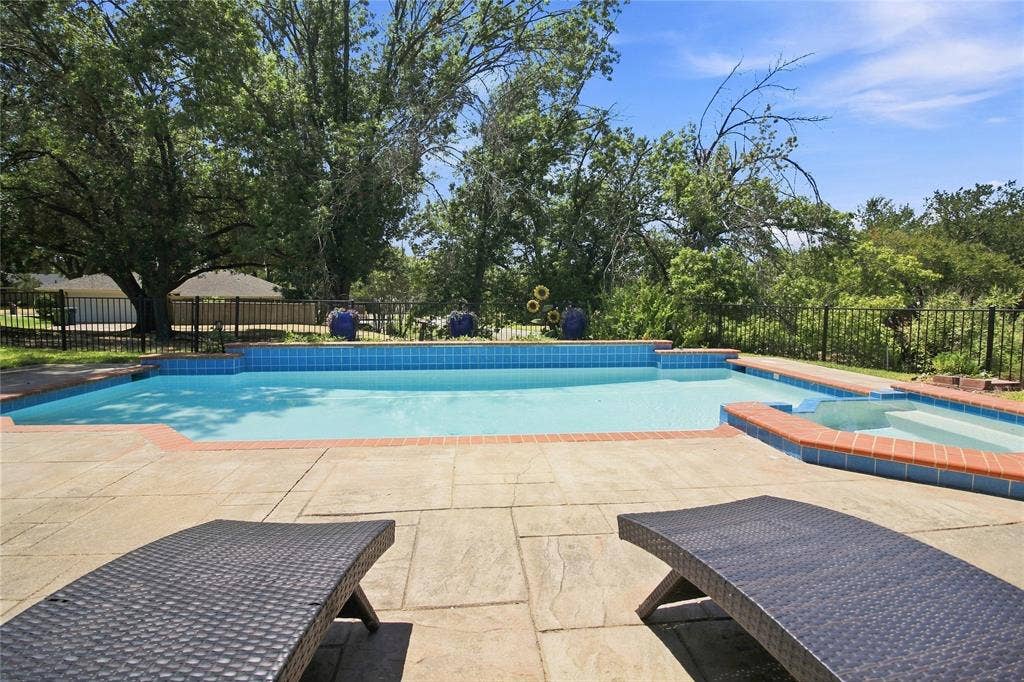 1417 Sun Valley Drive, Garland, TX 75043 Outdoor swimming pool with integrated spa, surrounded by a stone paver patio