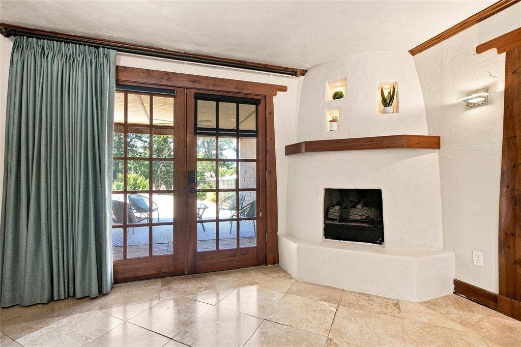 1417 Sun Valley Drive, Garland, TX 75043 Primary bedroom with tile flooring, built-in fireplace, exposed wood trim, recessed wall niches, and dual ceiling fans with integrated lighting
