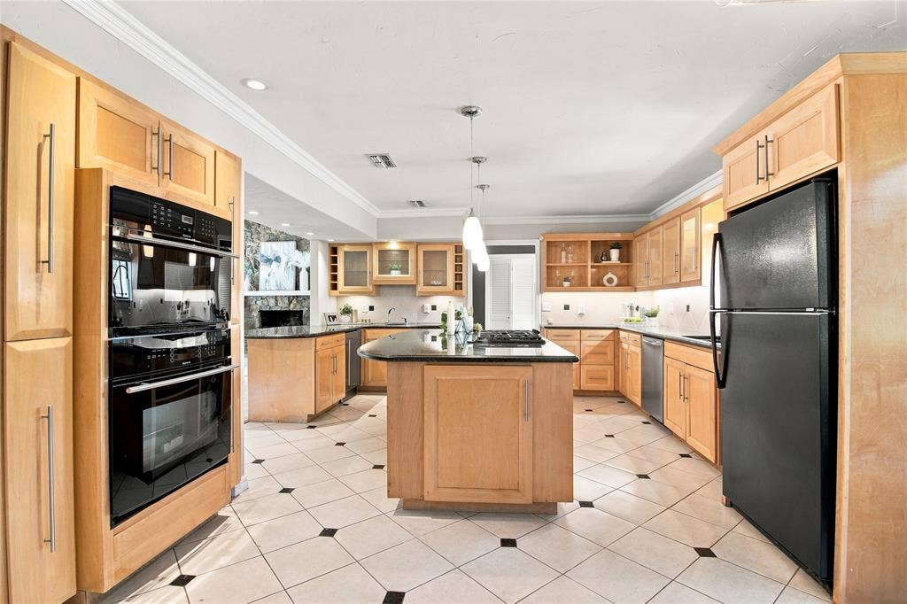 1417 Sun Valley Drive, Garland, TX 75043 Kitchen featuring light wood cabinetry, black appliances, a central island with a cooktop, pendant lighting, and tile flooring