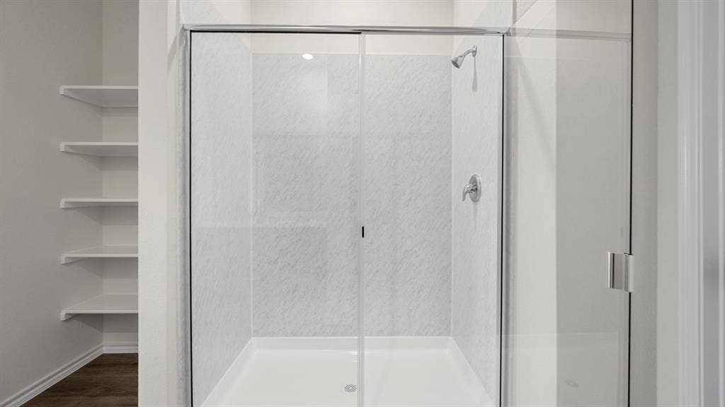 5033 Shumard Drive, Lindale, TX 75771 Glass-enclosed shower with a textured white surround, chrome shower fixtures, recessed lighting, and adjacent built-in shelving