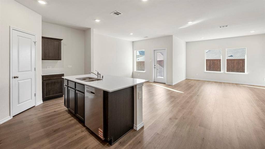 5033 Shumard Drive, Lindale, TX 75771 Open-concept layout featuring wood-finish flooring, recessed lighting, a kitchen island with integrated sink, stainless steel dishwasher, and white countertops