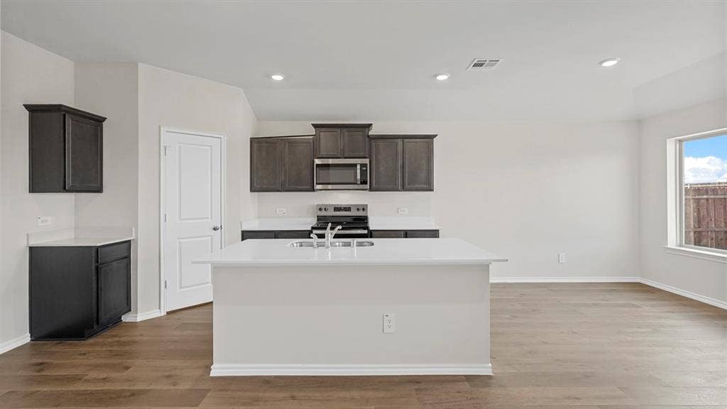 219 Yates Street, Bullard, TX 75757 Kitchen with recessed lighting, dark cabinetry, stainless steel appliances, and a central island with a sink
