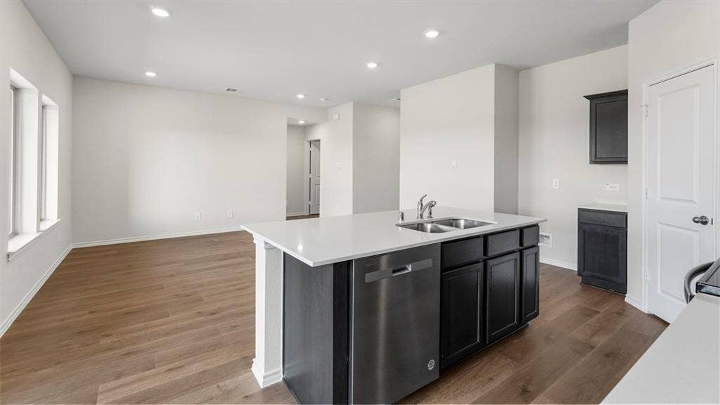 219 Yates Street, Bullard, TX 75757 Open-concept living area featuring wood-finish flooring, recessed lighting, and a kitchen island with a double sink, stainless steel dishwasher, and dark cabinetry