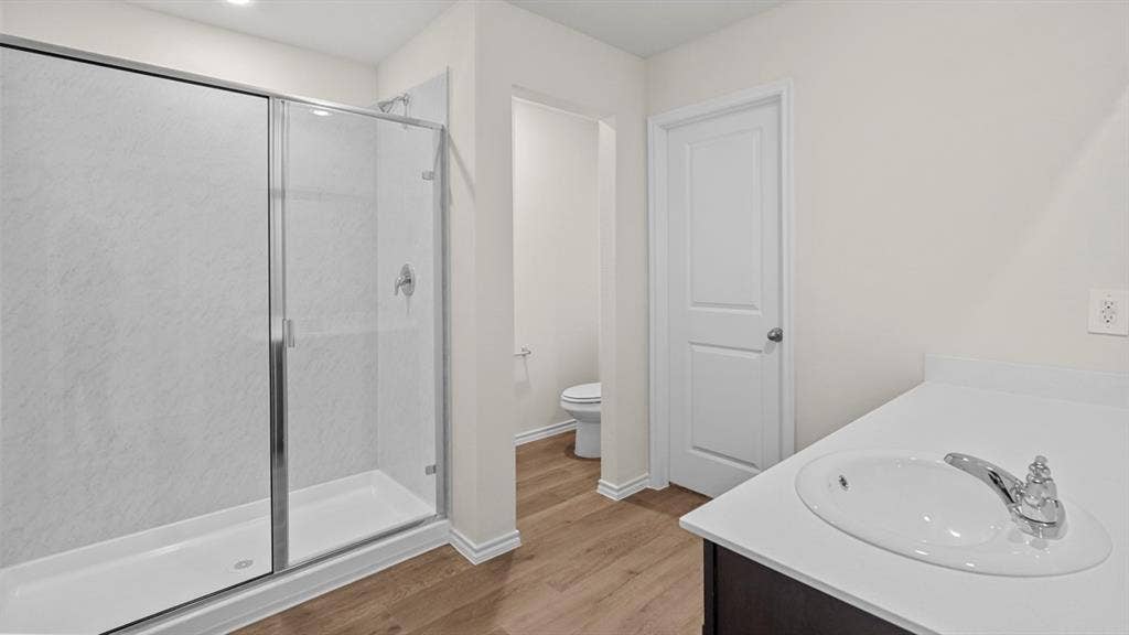 219 Yates Street, Bullard, TX 75757 Glass-enclosed shower with a textured white surround, single vanity with an integrated sink, white countertop, and wood-finish flooring