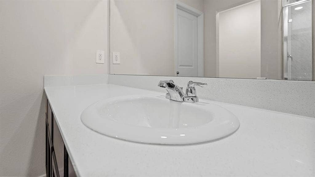 219 Yates Street, Bullard, TX 75757 Vanity with an integrated basin, chrome faucet, and expansive wall mirror