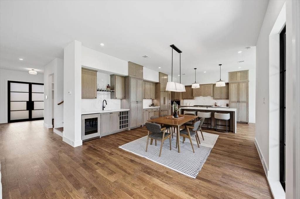 4320 Concho Street, Dallas, TX 75206 Open-concept living area with wood-finish flooring, a contemporary kitchen island, a built-in wet bar, and sleek pendant lighting